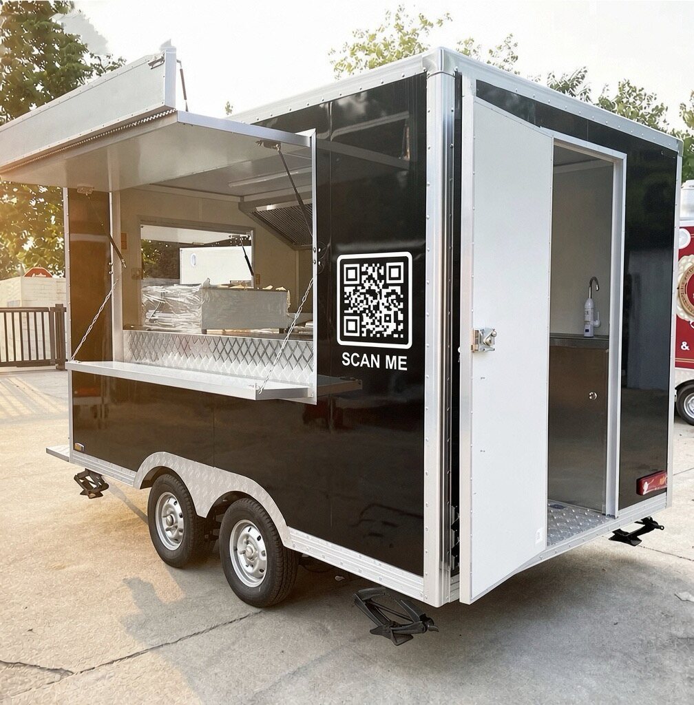 A SCAN ME QR decal on the side of a black food trailer