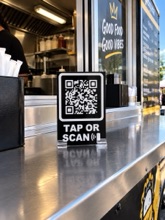 The tap-or-scan sign on a food truck counter